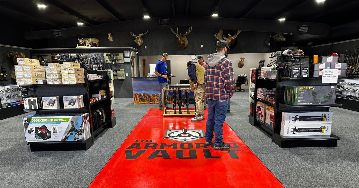 Inside The Armored Vault in Claremore: gun racks, ammo shelves, and the red logo floor runner